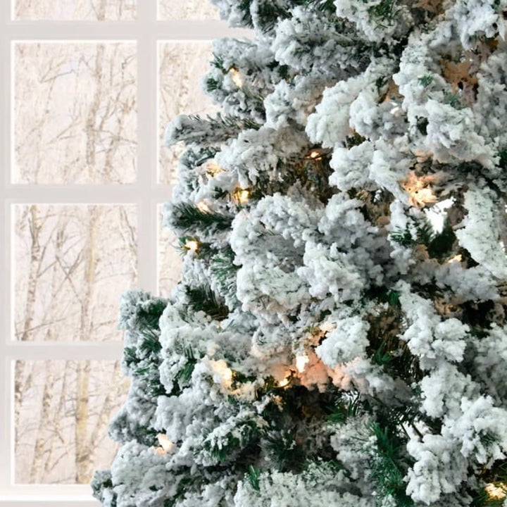 Besneeuwde kerstboom met witte lampjes