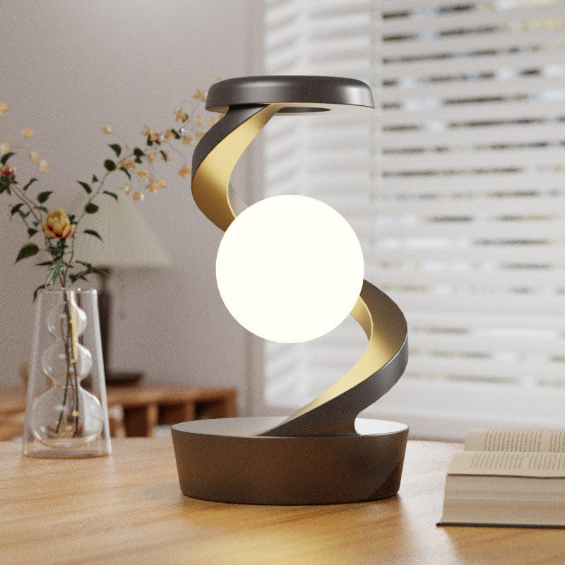 Draaiende maanlamp in metalen spiraal op bureau
