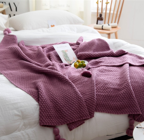 Gebreide plaid met pompons over de bank