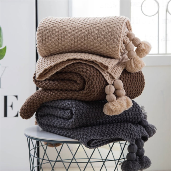 Gebreide plaid met pompons over de bank