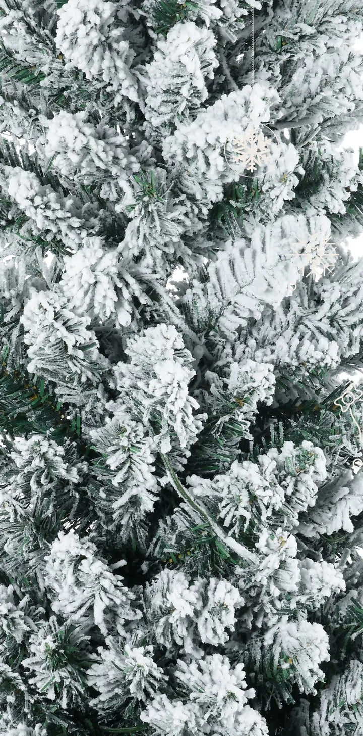 Smalle besneeuwde kerstboom met warmwitte lichtjes