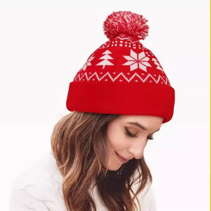 Gebreide kerstmuts met pompon en sneeuwvlokken