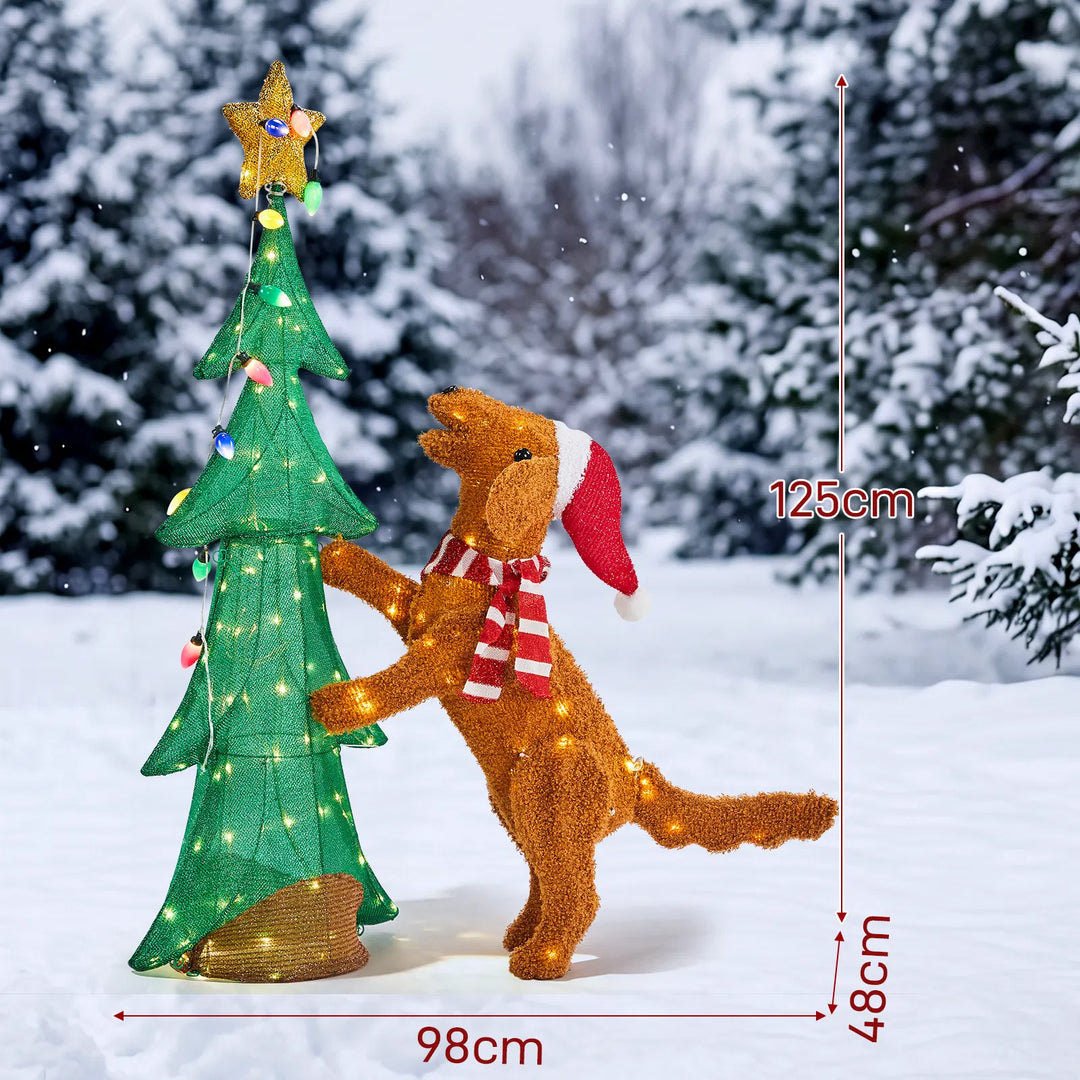 Verlichte kerstboom met klimmende pluchen hond