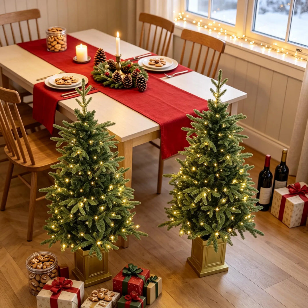 Twee kerstboompjes in gouden potten met lichtjes